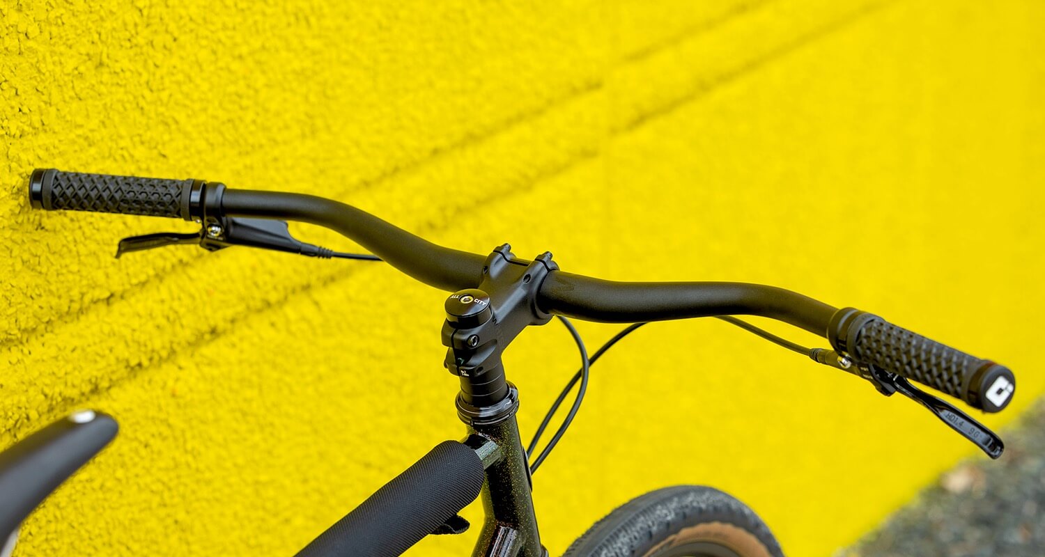 Closeup view of a Whisky Scully handlebar against a yellow concrete wall.