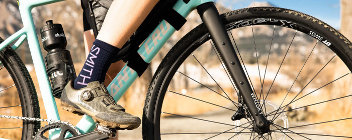 Cyclist stands over a bike with one foot on a pedal. The bike features the Whisky CXLR fork.