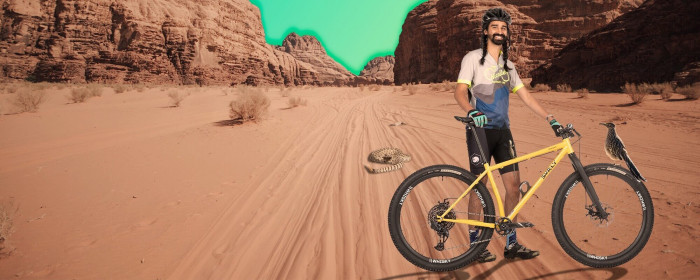 Cyclist, photoshopped onto a desert landscape, stands with a bike alongside a rattlesnake and bird