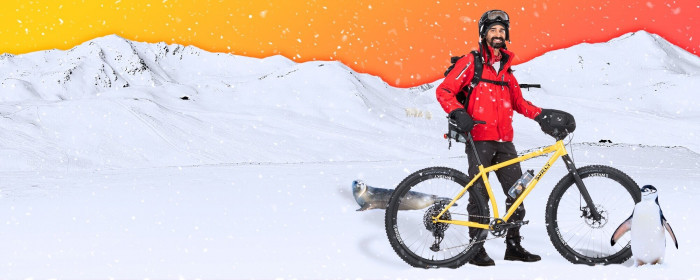 Cyclist, photoshopped onto a snowy arctic landscape, stands with a bike alongside a penguin and seal.