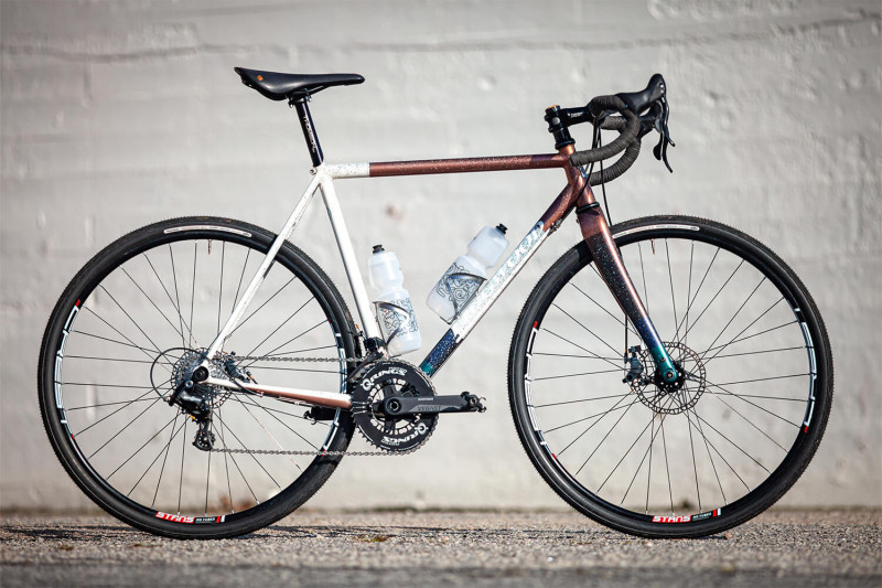 Profile view of the Dogwood Cycleworx Copper Gravel bike against a white brick wall. 
