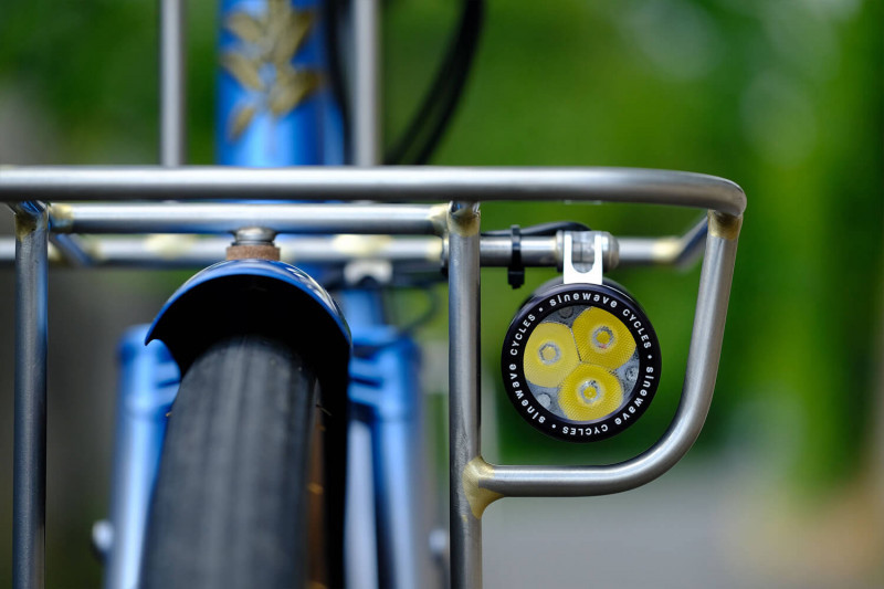 Closeup shot of the headlight attached to the front rack on the Victore Cycles blue randonneur bike.