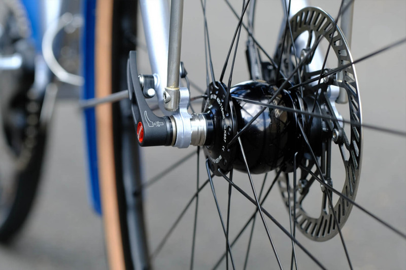 Closeup of the front hub and disc brake rotor on the Victore Cycles blue randonneur bike.