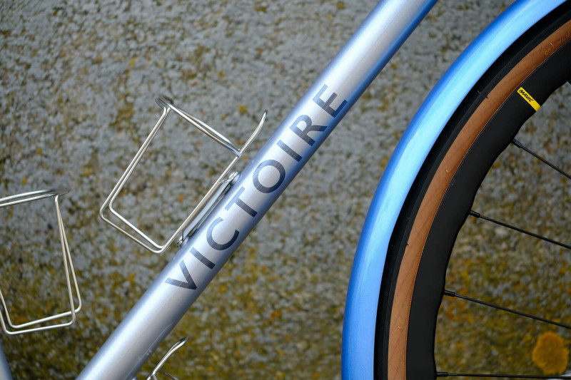 Closeup of the down tube with water bottle cage on the Victore Cycles blue randonneur bike.